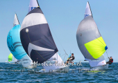Flying Dutchman World Championship 2026 - drei Boote halten unter Spinnaker auf die Zielmarke zu.
